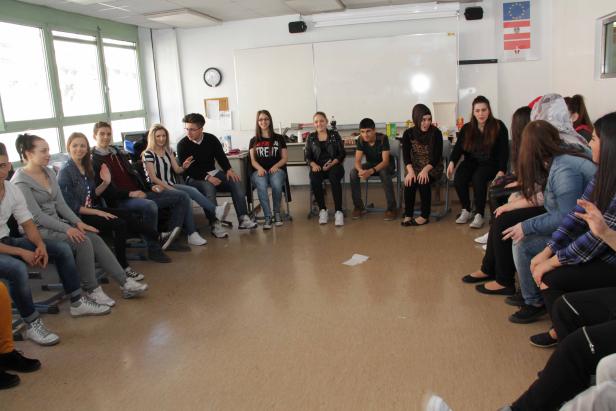 Eine Gruppe von Studenten sitzt im Kreis in einem Klassenzimmer.