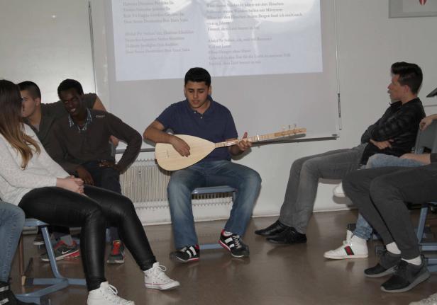 Ein junger Mann spielt vor einer Gruppe von Zuhörern auf einer Saz, einem traditionellen türkischen Saiteninstrument.