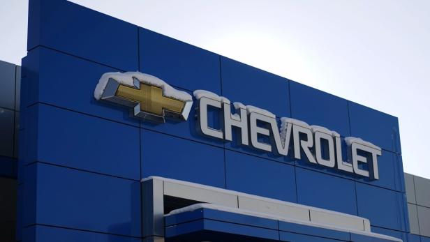 The sign at a Chevrolet General Motors store is se Das Chevrolet-Logo und der Schriftzug an einem blauen Gebäude sind mit Schnee bedeckt.