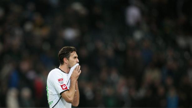 Ein Fußballspieler wischt sich mit einem Tuch den Schweiß von der Stirn.