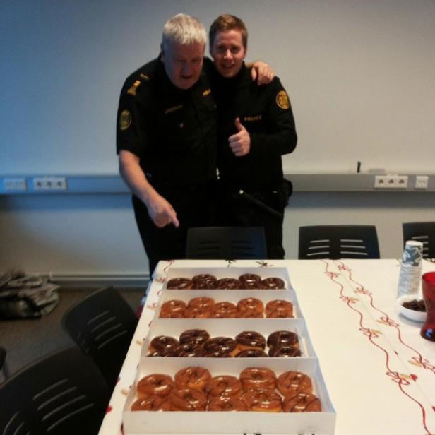 Zwei Polizisten stehen an einem Tisch mit vielen Donuts.