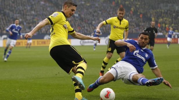 Ein Fußballspieler in Gelb grätscht nach dem Ball, während ein Spieler in Blau zu Fall kommt.