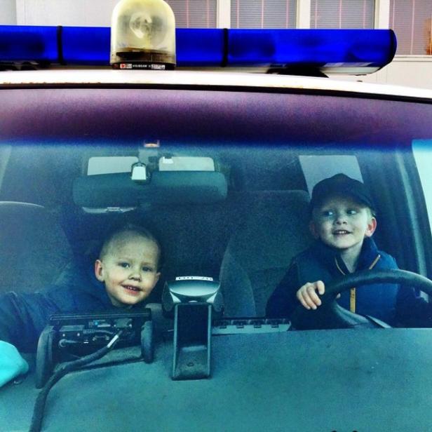 Zwei kleine Jungen sitzen in einem Polizeiauto.