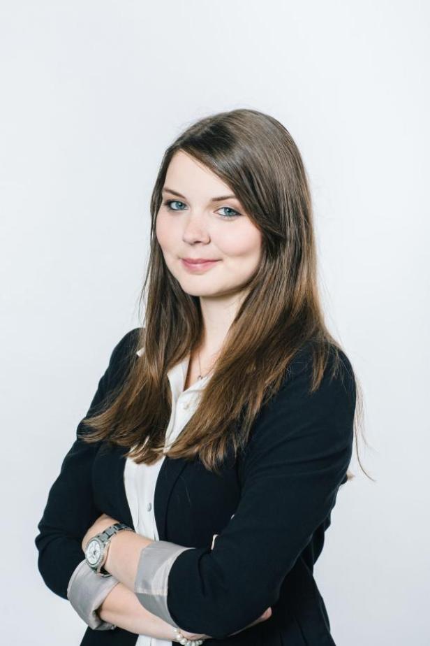 Eine junge Frau mit verschränkten Armen, gekleidet in Blazer und Bluse.