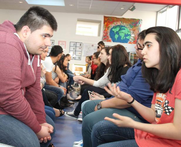 Eine Gruppe von Studenten sitzt im Kreis und diskutiert.