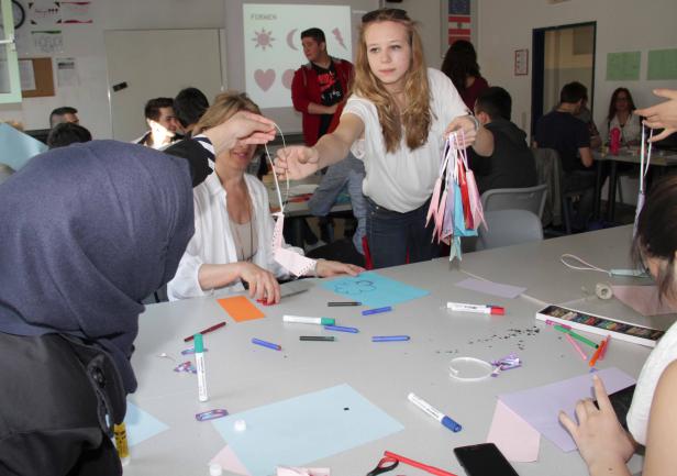 Eine Gruppe von Menschen bastelt mit Papier und Stiften an einem Tisch.