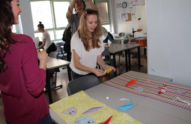 Mehrere Personen basteln in einem Klassenzimmer mit Papier und Klebstoff.