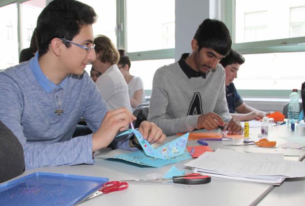 Schüler basteln und dekorieren Papier auf einem Tisch.