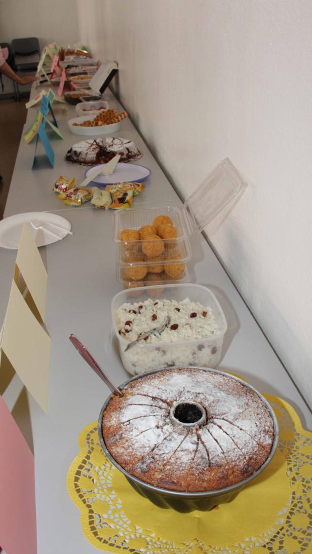 Ein Tisch mit verschiedenen Kuchen und Süßspeisen, darunter ein Gugelhupf mit Puderzucker.