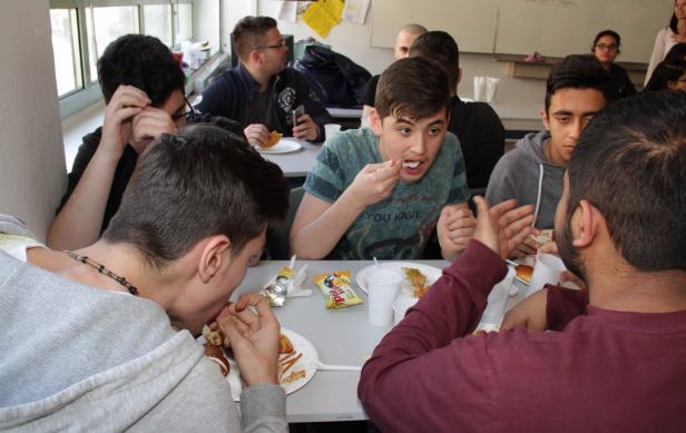 Eine Gruppe junger Leute isst gemeinsam an einem Tisch.