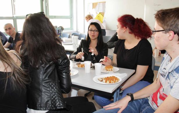 Eine Gruppe von Leuten sitzt an einem Tisch und isst Waffeln.