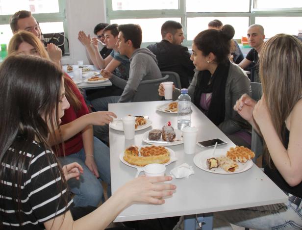 Eine Gruppe von Menschen sitzt an einem Tisch mit Waffeln und anderen Süßspeisen.