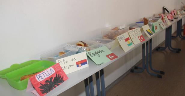 Ein Tisch mit verschiedenen Speisen und handgezeichneten Flaggen, die die Herkunft der Gerichte kennzeichnen.