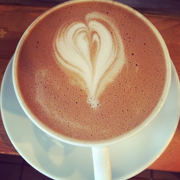 Eine Tasse heißer Kakao mit einem Herz aus Milchschaum auf einem Untertasse.