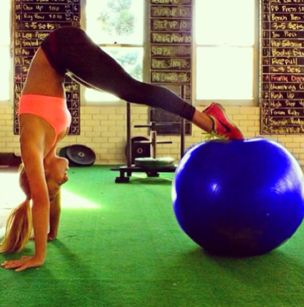 Eine Frau macht eine Übung, bei der sie mit den Füßen auf einem Gymnastikball steht.