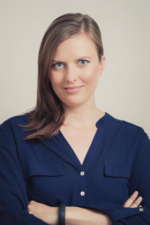 Eine Frau mit blauen Augen und braunem Haar lächelt in die Kamera.