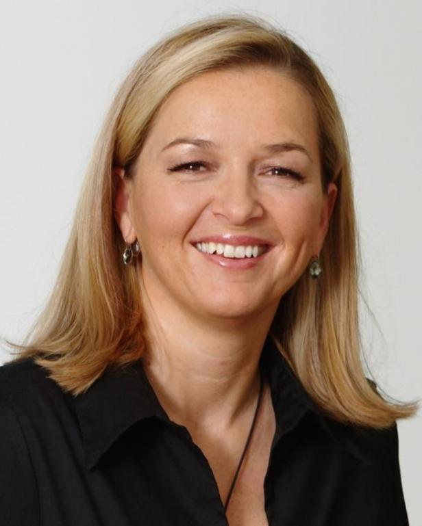 Porträt einer lächelnden Frau mit blonden Haaren und schwarzem Hemd.