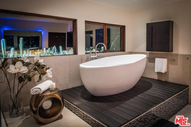 Ein modernes Badezimmer mit einer freistehenden Badewanne und einem Fenster mit Kakteenblick.