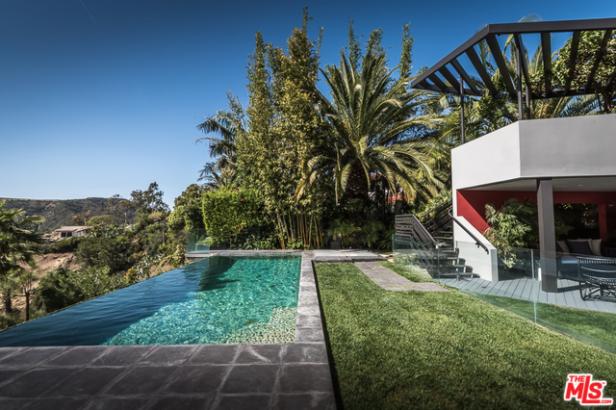 Ein Infinity-Pool grenzt an ein modernes Haus mit üppiger tropischer Vegetation.