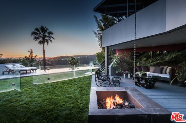 Ein moderner Garten mit Pool, Feuerstelle und Blick auf die Landschaft bei Sonnenuntergang.
