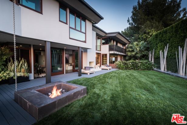 Ein modernes Haus mit einem gepflegten Garten und einer Feuerstelle im Freien.