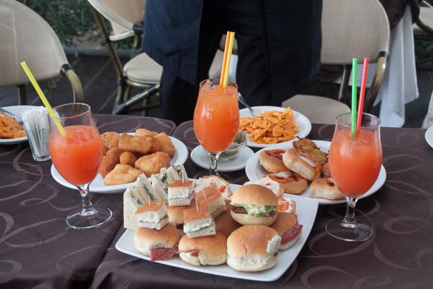 Ein Tisch mit verschiedenen Speisen und Getränken, darunter Sandwiches, Pasta und Cocktails.