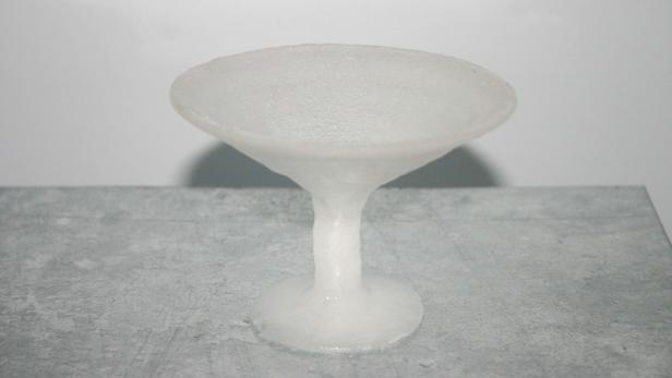 Ein gefrorenes Cocktailglas steht auf einer grauen Oberfläche.