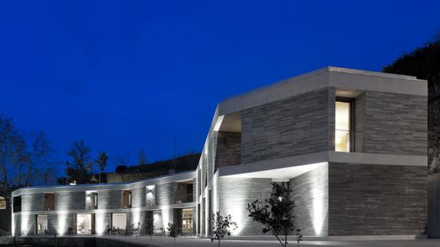 Ein modernes, zweistöckiges Gebäude mit Steinverkleidung bei Dämmerung.