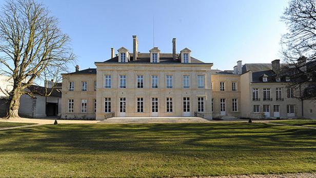 Ein großes, helles Herrenhaus mit einem gepflegten Rasen davor.