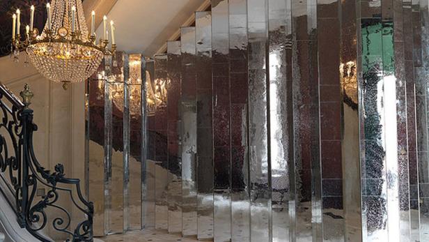 Ein Treppenhaus mit einem Kristalllüster und einer Wand aus Spiegeln.