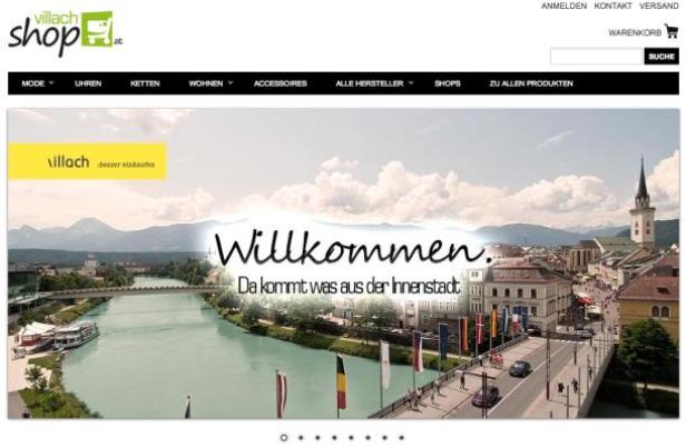 Panorama von Villach mit der Drau und Bergen im Hintergrund.