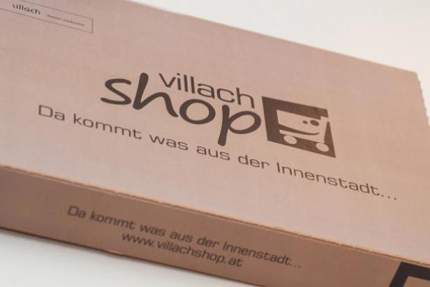 Ein Karton mit dem Logo des „Villach Shop“ und dem Slogan „Da kommt was aus der Innenstadt…“.
