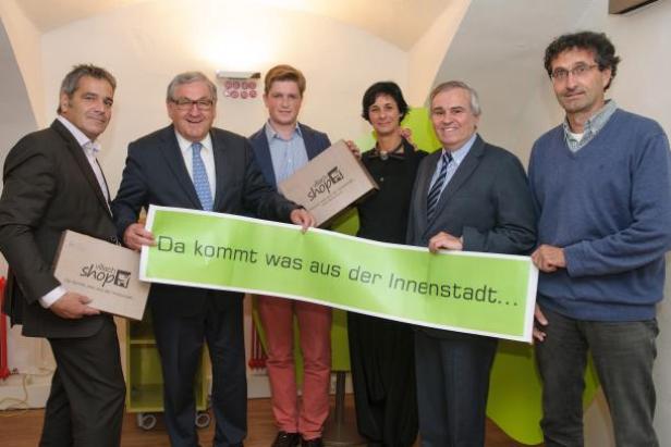 Eine Gruppe von Personen hält ein Schild mit der Aufschrift „Da kommt was aus der Innenstadt…“.