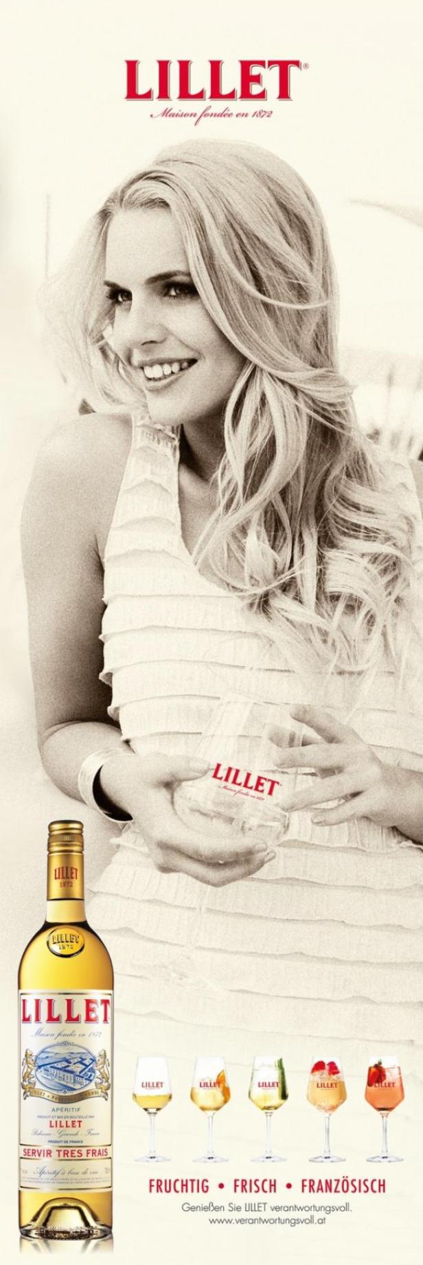 Eine Frau lächelt und hält ein Glas Lillet, während eine Flasche Lillet im Vordergrund steht.