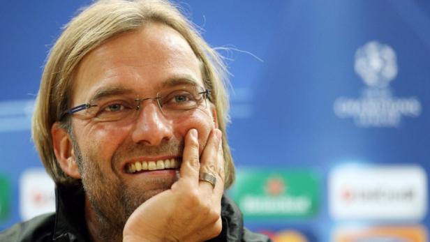 Jürgen Klopp lächelt mit seiner Hand an der Wange.