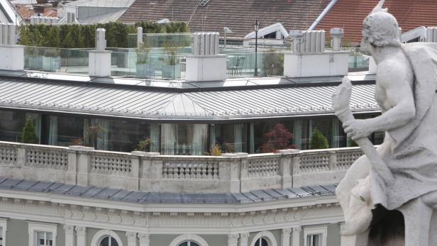 Eine Statue vor einem Gebäude mit Dachterrasse.