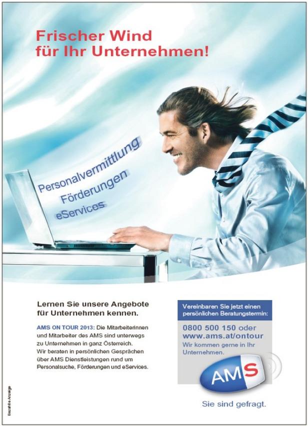 Ein lächelnder Mann mit wehendem Haar und Krawatte arbeitet am Laptop.