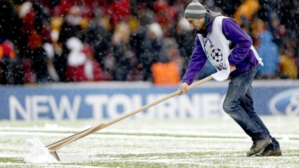 Ein Mann räumt Schnee von einem Fußballfeld.