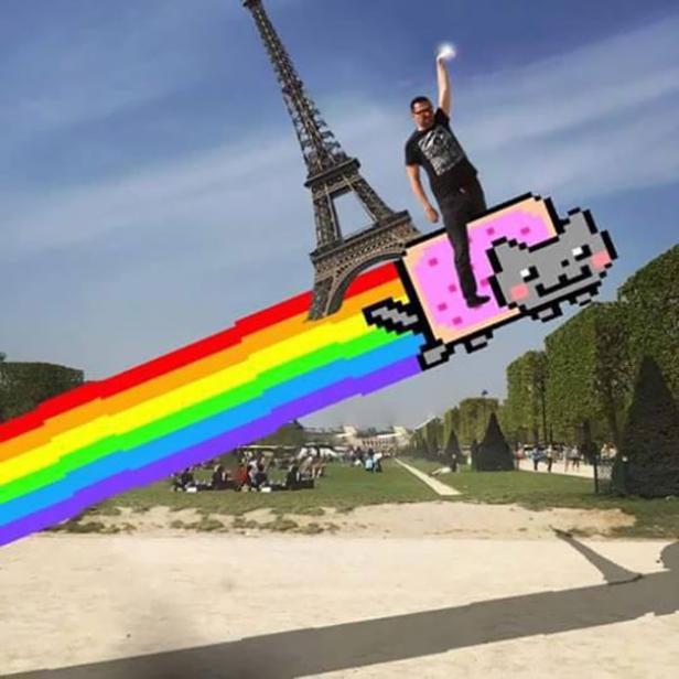 Ein Mann reitet auf einer Nyan Cat mit Regenbogen hinter dem Eiffelturm in Paris.