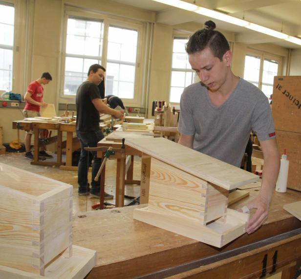 Ein junger Mann arbeitet in einer Werkstatt an einem Holzprojekt.