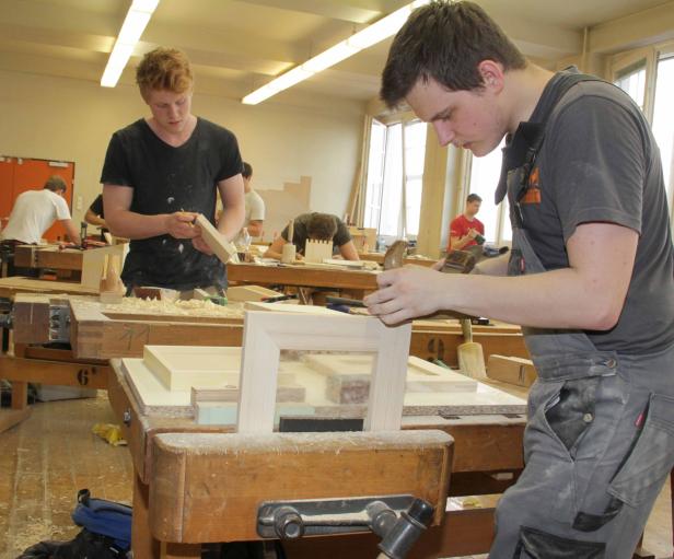Zwei junge Männer arbeiten in einer Werkstatt mit Holz.