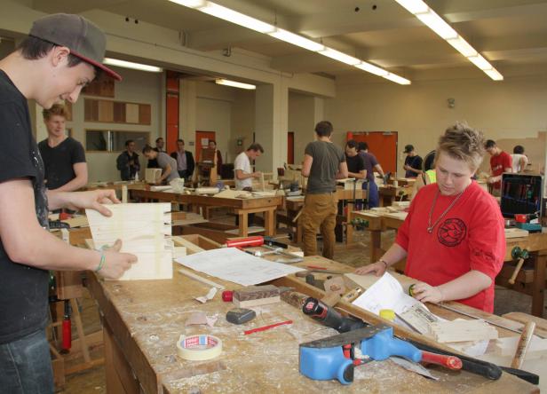 Schüler arbeiten in einer Werkstatt an Holzarbeiten.