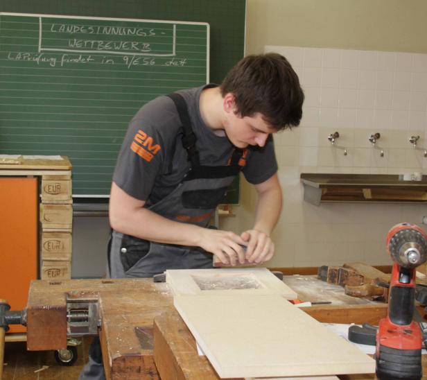 Ein junger Mann arbeitet in einer Werkstatt an einem Holzrahmen.