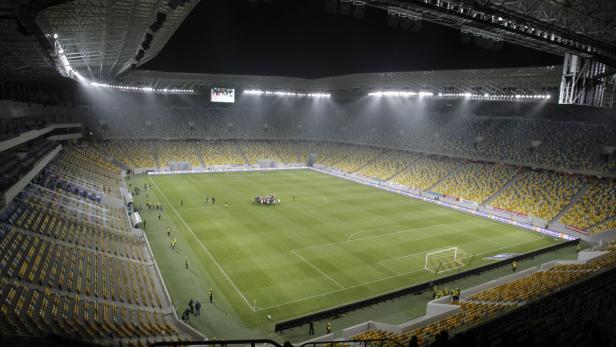 Das leere Olympiastadion in Kiew mit gelb-blauen Sitzen und hell erleuchtetem Spielfeld.