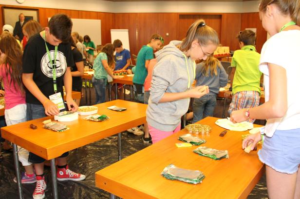 Kinder stehen an Tischen und stellen Süßigkeiten her.