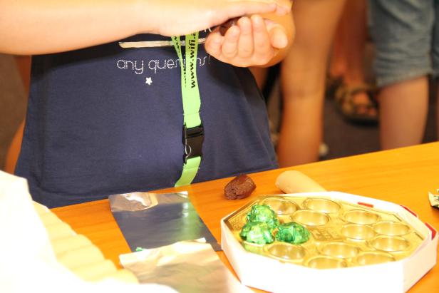 Ein Kind formt eine Praline über einer Schachtel mit grünen Pralinen.