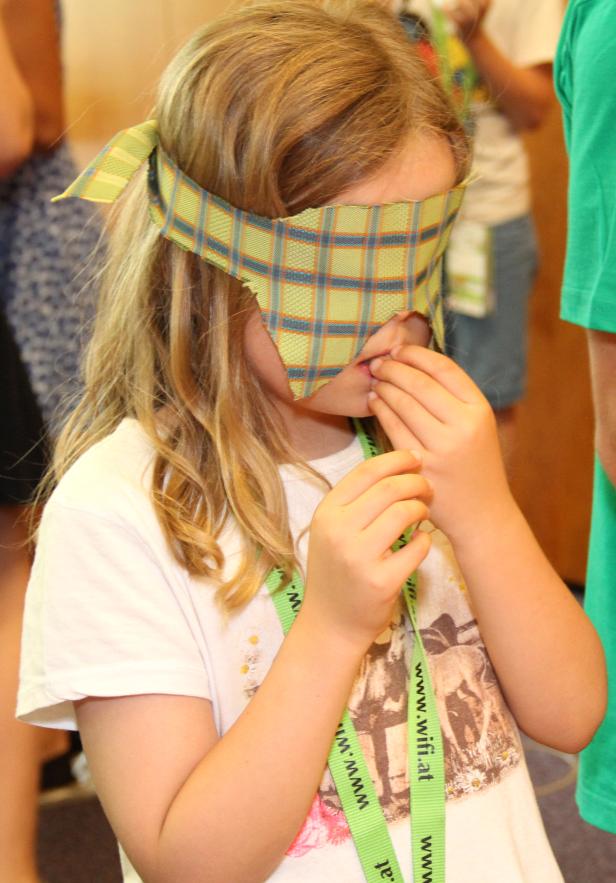 Ein Mädchen mit verbundenen Augen scheint an einem Spiel teilzunehmen.