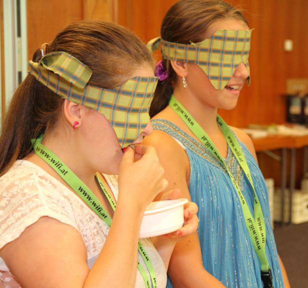 Zwei Mädchen mit verbundenen Augen nehmen an einer Geschmacksprüfung teil.
