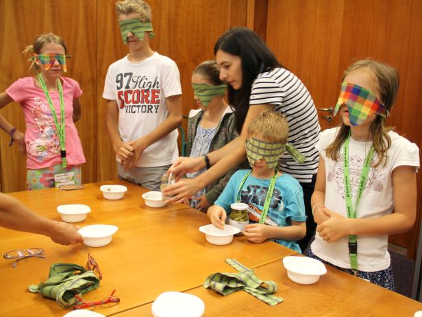 Kinder nehmen mit verbundenen Augen an einem Geschmacks-Test teil.