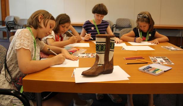 Vier Mädchen zeichnen einen Stiefel in einem Klassenzimmer.